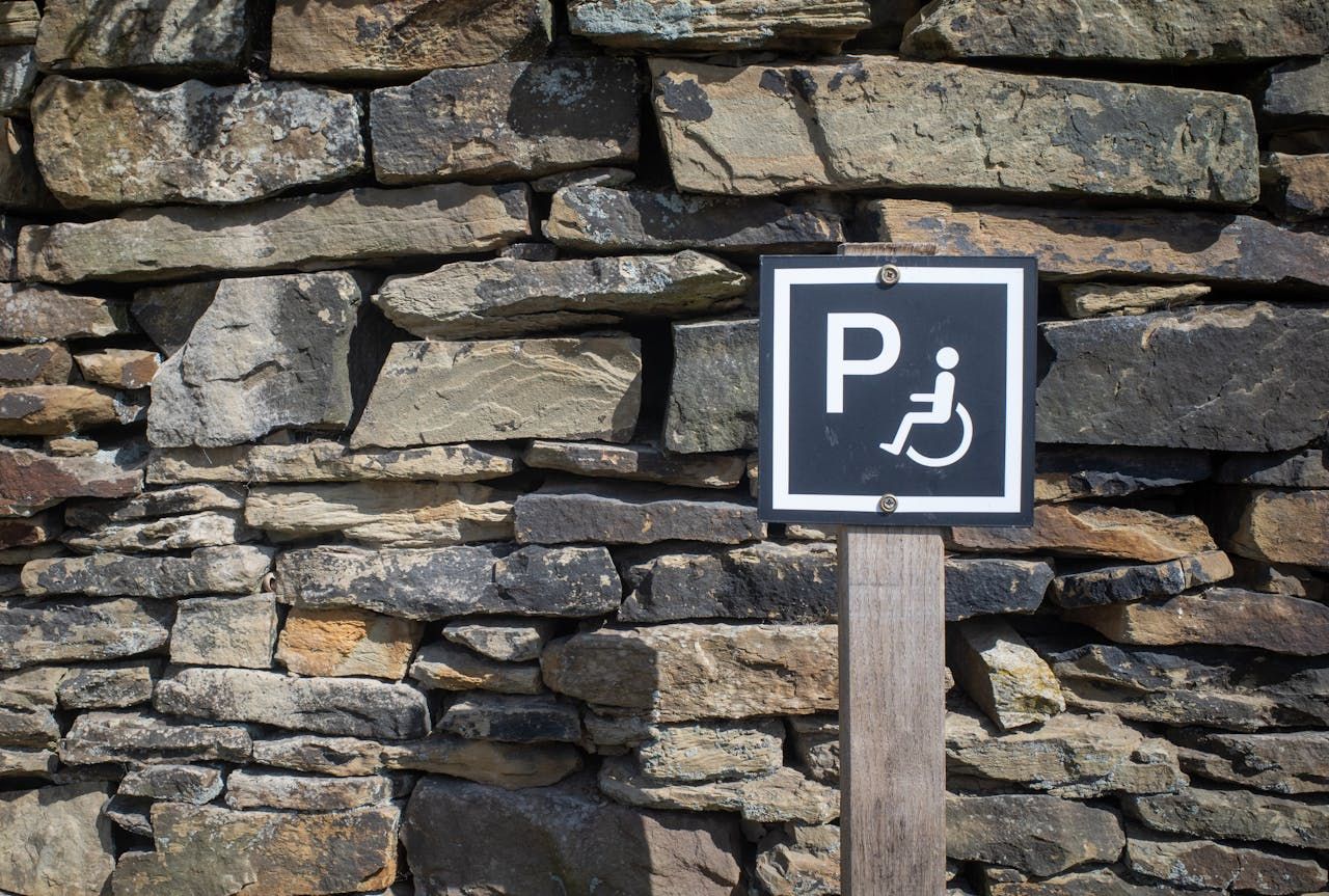 Una señal de estacionamiento con un símbolo de silla de ruedas, indicando estacionamiento accesible.